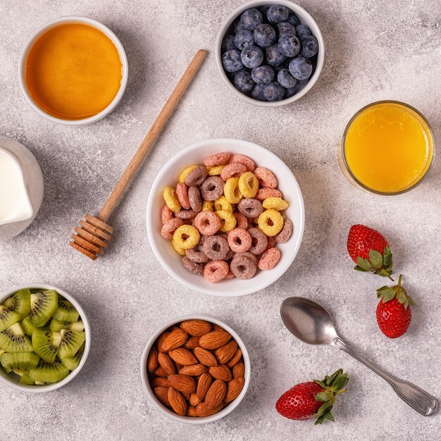 Colazione con anelli di cereali colorati, frutta, latte, succo di frutta