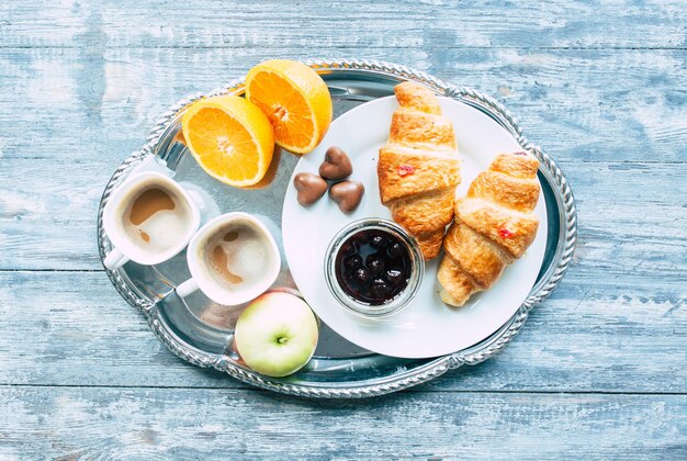 Colazione con caffè, croissant, caramelle di mele, arance e cioccolato