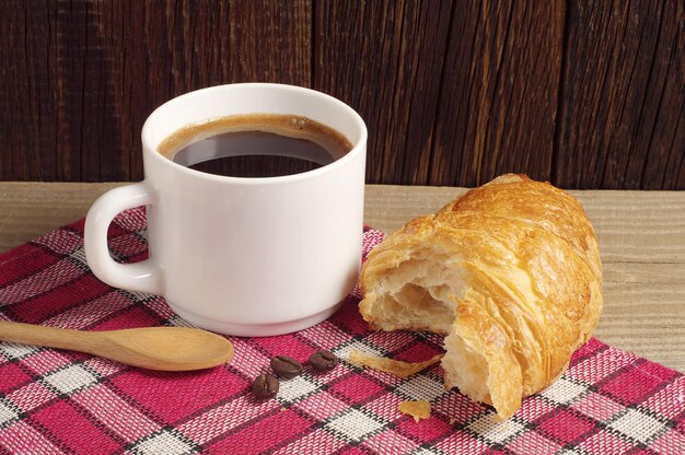 Colazione con caffè e croissant sul tavolo di legno scuro