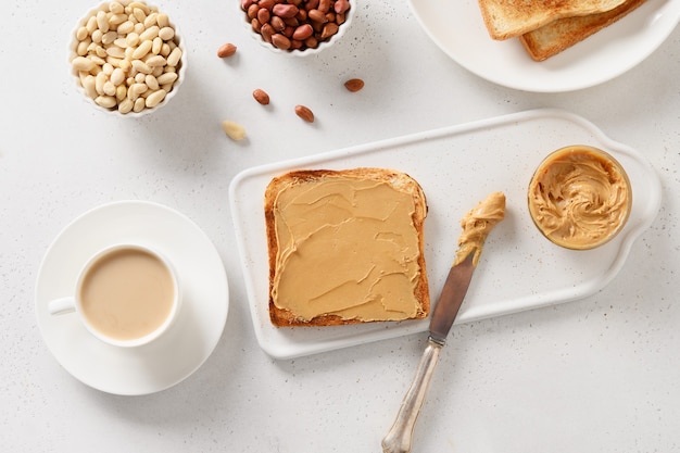 Colazione con caffè e pane tostato croccante con pasta di arachidi.