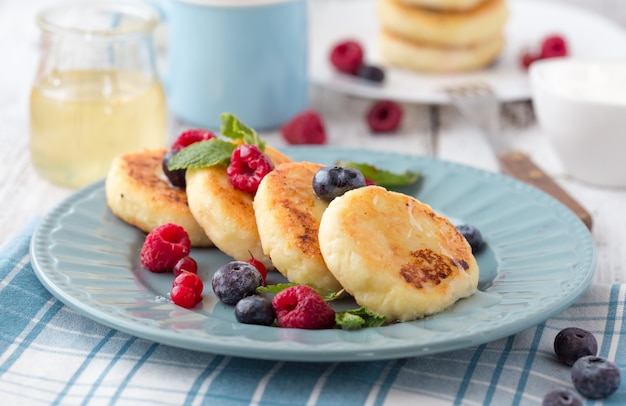 Colazione con cheesecake, frutti di bosco freschi Frittelle di formaggio o frittelle di cagliata. Syrniki russo o sirniki