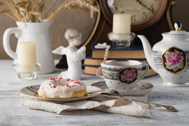 Colazione con ciambella e tazza di tè. Vecchi libri sul tavolo