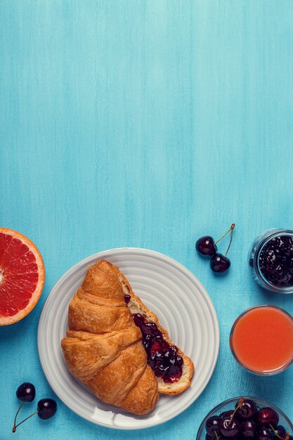 Colazione con cornetto, marmellata, frutta e succo.