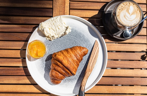 colazione con croissant marmellata di arance e burro con cappuccino in un caffè all'aperto mattina di sole