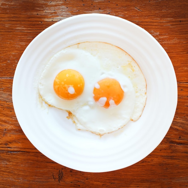 Colazione con due uova fritte in piatto bianco