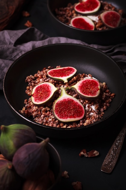 Colazione con muesli e fichi. Piatti neri con una colazione fresca e sana. Cibo salutare