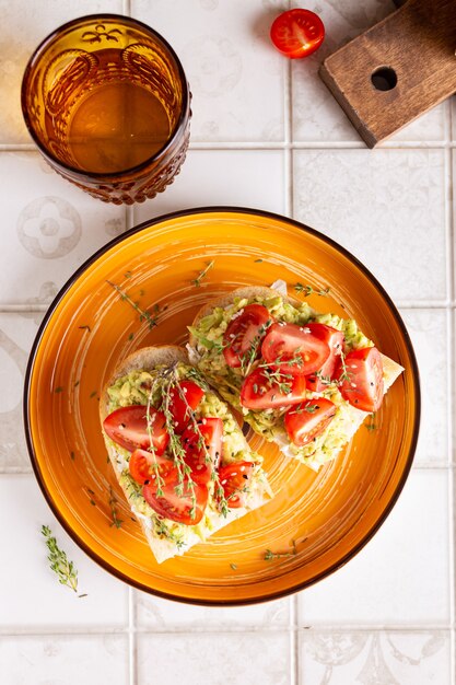 Colazione con panini vegetariani con avocado e pomodori su un grande piatto arancione