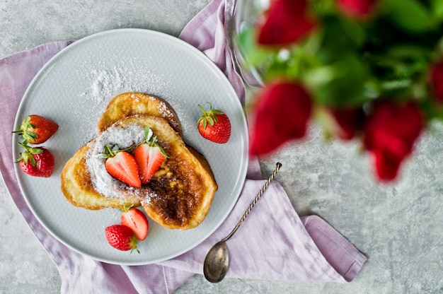 Colazione con toast e fragole francesi, vaso con rose.