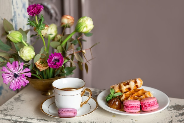 Colazione con una tazza di tè, waffle al miele e amaretti