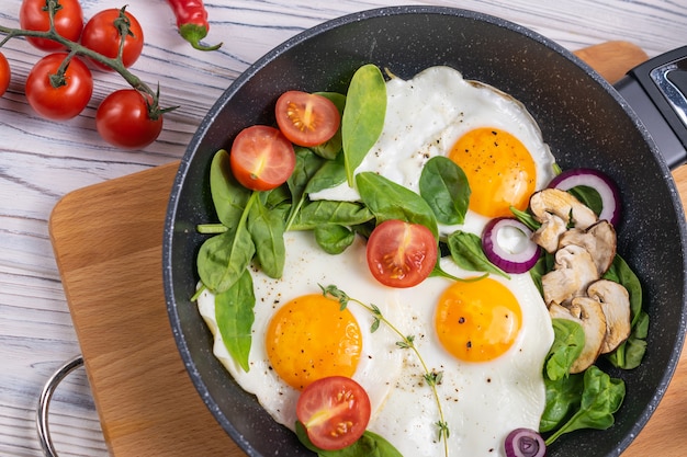 Colazione con uova, pomodori con funghi e foglie di spinaci freschi