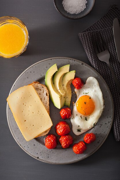 colazione con uovo fritto vicino avocado e pomodori con formaggio