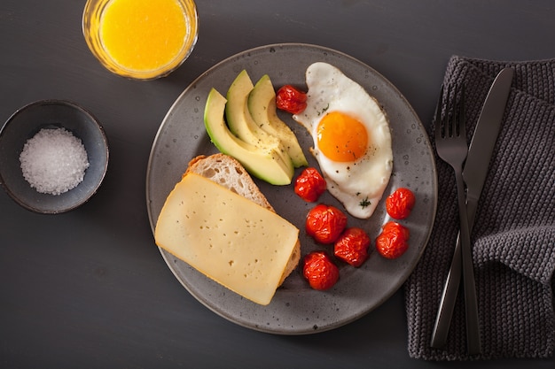 colazione con uovo fritto vicino avocado e pomodori con formaggio