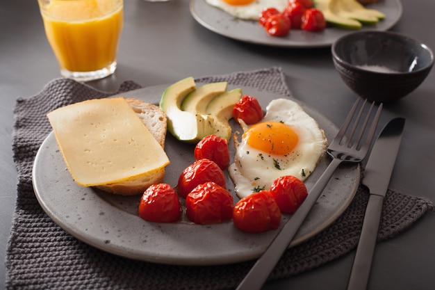 colazione con uovo fritto vicino avocado e pomodori con formaggio