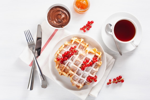 Colazione con waffle, frutti di bosco, marmellata, crema al cioccolato e tè. Vista dall'alto