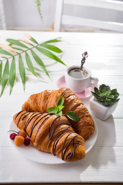 Colazione continentale croissant appena sfornato decorato con marmellata e cioccolato