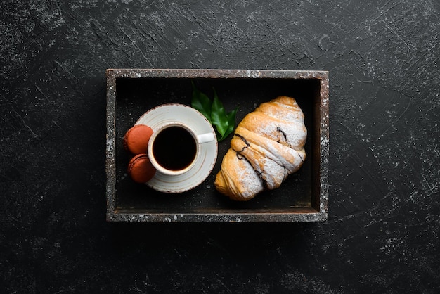 Colazione Croissant al caffè e amaretti Su uno sfondo di pietra nera Vista dall'alto Spazio libero per il testo