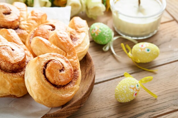 Colazione di Pasqua Holliday concept Coniglietto di Pasqua panini rotoli con cannella a base di pasta lievitata con glassa all'arancia decorazioni pasquali uova colorate su sfondo di legno vecchio Carta di Pasqua Holliday