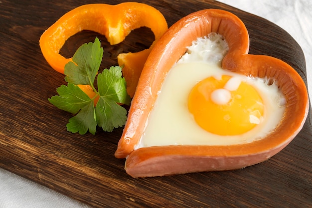 Colazione di San Valentino. salsiccia con uovo strapazzato a forma di cuore.