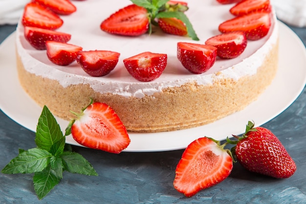 Colazione dolce deliziosa cheesecake con fragole fresche e menta ricetta fatta in casa senza cottura su un tavolo di pietra blu scuro Copia spazio