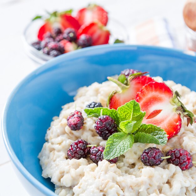 Colazione - farina d&#39;avena con miele e frutti di bosco, ciotola blu