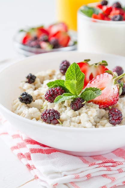 Colazione - farina d&#39;avena con miele e frutti di bosco, ciotola blu