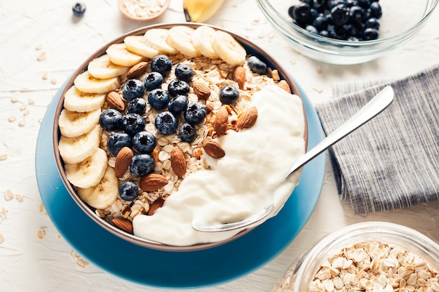 Colazione, farina d&#39;avena con mirtillo, mandorle e yogurt alla banana in una ciotola al mattino.