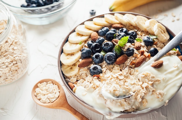 Colazione, farina d&#39;avena con mirtillo, mandorle e yogurt alla banana in una ciotola al mattino.