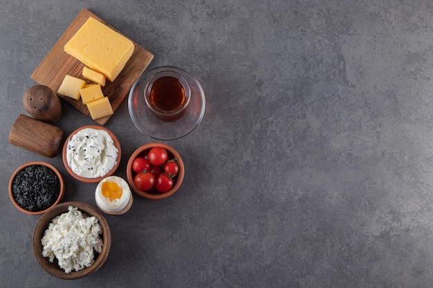 Colazione fatta in casa con uova sode, formaggio e tè nero sul tavolo di pietra.