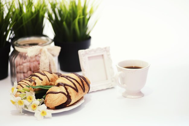 Colazione francese sul tavolo. Croissant al caffè con cioccolato e decanter con panna. Pasticceria fresca e caffè decaffeinato.