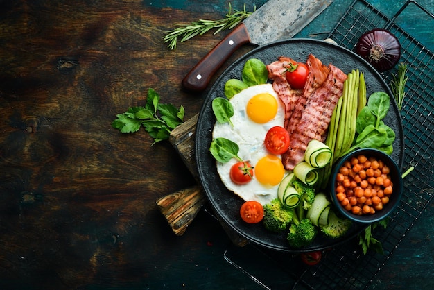 Colazione inglese ceci avocado uova strapazzate pancetta verdure su una lastra di pietra nera Vista dall'alto Spazio libero per il testo