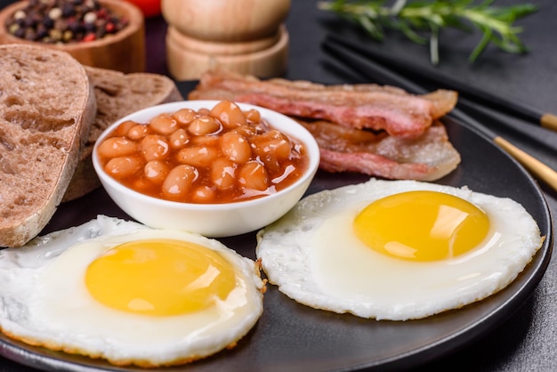 Colazione inglese con uova fritte pancetta fagioli pomodori spezie ed erbe aromatiche