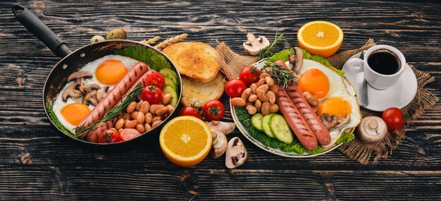 Colazione inglese uova fritte fagioli pomodori funghi pancetta e toast Vista dall'alto su uno sfondo di legno