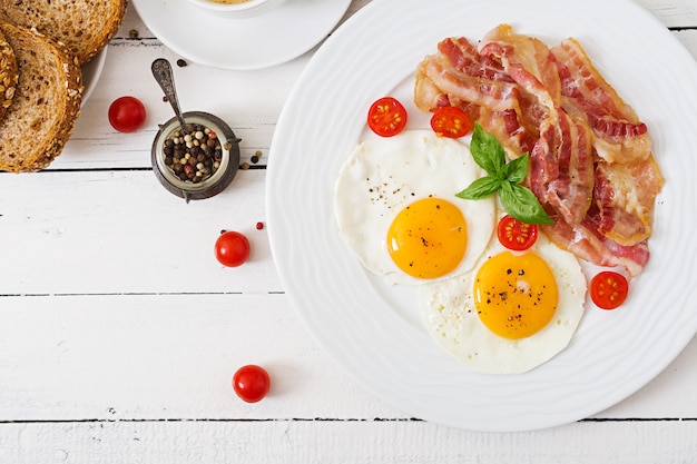 Colazione inglese - uovo fritto, pomodori e pancetta. tavolo