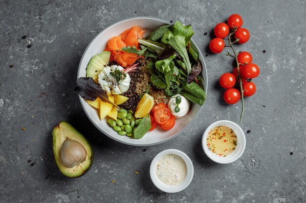 Colazione leggera e sana, pranzo di lavoro. Colazione con uovo in camicia, grano saraceno, pesce rosso, insalata fresca, cetrioli e pomodorini, concetto di pranzo di lavoro.