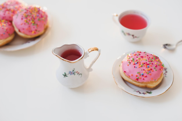 colazione mattutina con bevanda rosa colorata e ciambelle su tavola bianca festa di compleanno