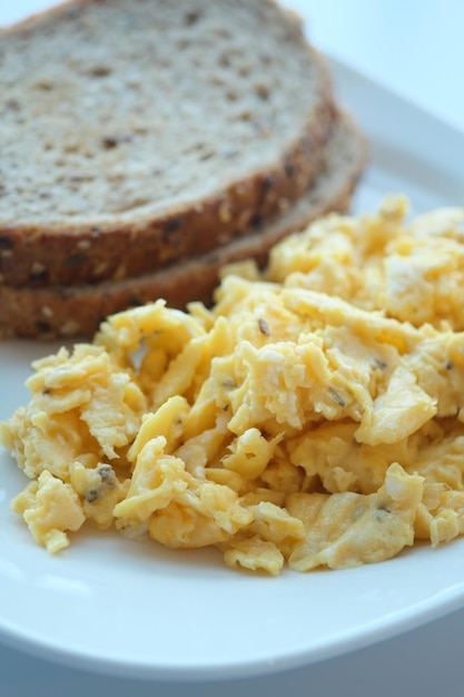 Colazione mattutina con uova strapazzate su un pane sul piatto bianco