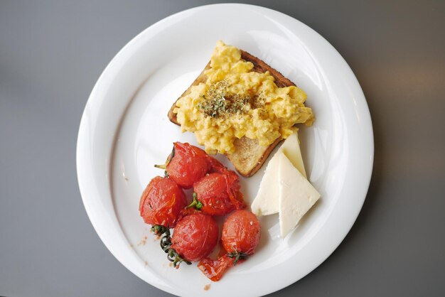 Colazione mattutina con uova strapazzate su un pane sul piatto bianco