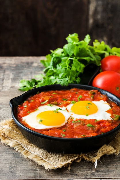 Colazione messicana: rancheros di Huevos in padella di ferro sul tavolo di legno