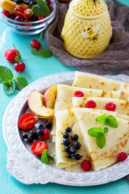 Colazione pancake con miele e frutti di bosco freschi di ribes fragole nettarine