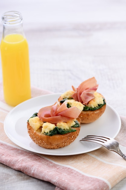 Colazione. Panino al forno con formaggio, spinaci, prosciutto e succo d'arancia