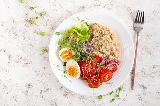 Colazione porridge di farina d'avena con uova bollite e verdure fresche cibo sano e equilibrato cibo alla moda vista superiore piatto