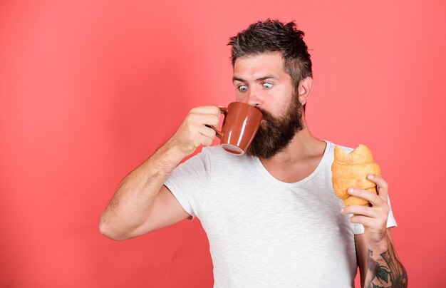 Colazione preferita Hipster barbuto gustare colazione bere caffè Concetto di tradizione mattutina Croissant appena sfornato Colazione deliziosa Colazione malsana ma gustosa Abbinamento perfetto Senti la fame