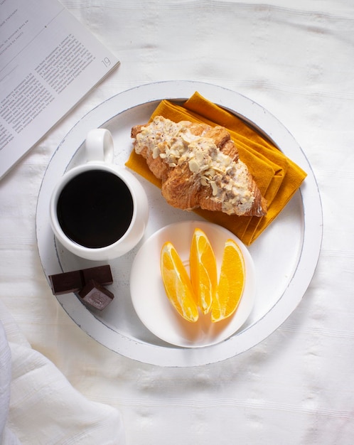 Colazione romantica caffè mattutino a letto arance e croissant su un vassoio di legno bianco