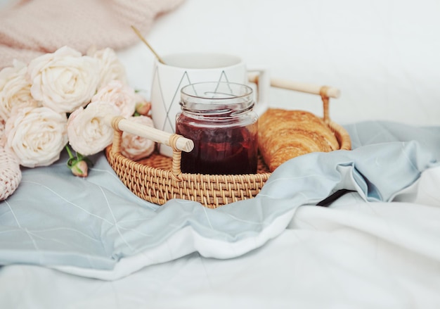 Colazione romantica con caffè, croissant e fiori di rosa.