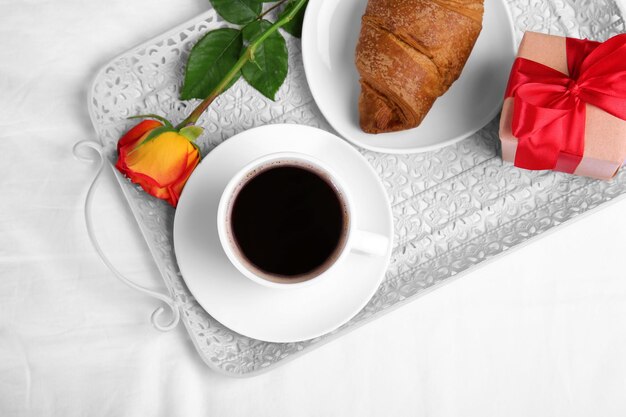 Colazione romantica con caffè e croissant sul vassoio in camera da letto Concetto di luna di miele