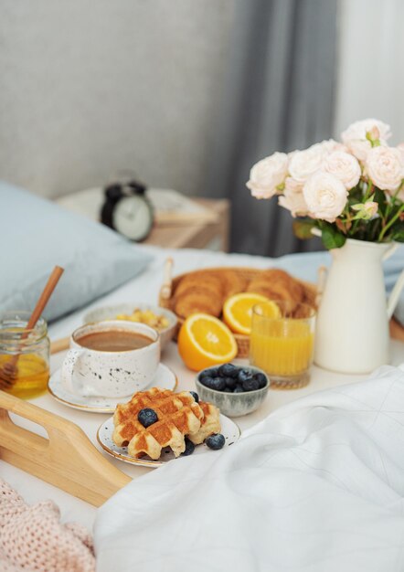 Colazione romantica con caffè waffle succo d'arancia e fiori di rosa