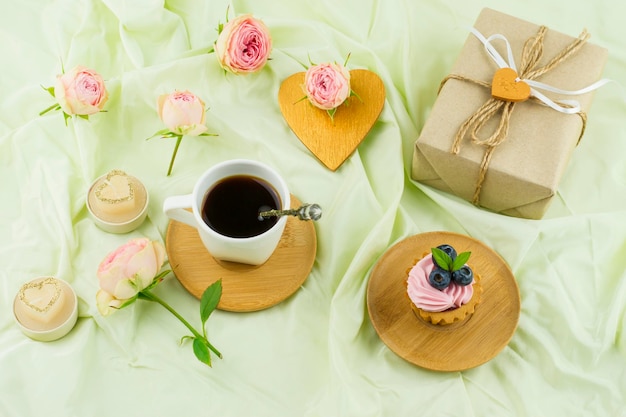 Colazione romantica per San Valentino. confezione regalo, boccioli di rosa, cuore, tazza di caffè appena fatto. sfondo pastello.