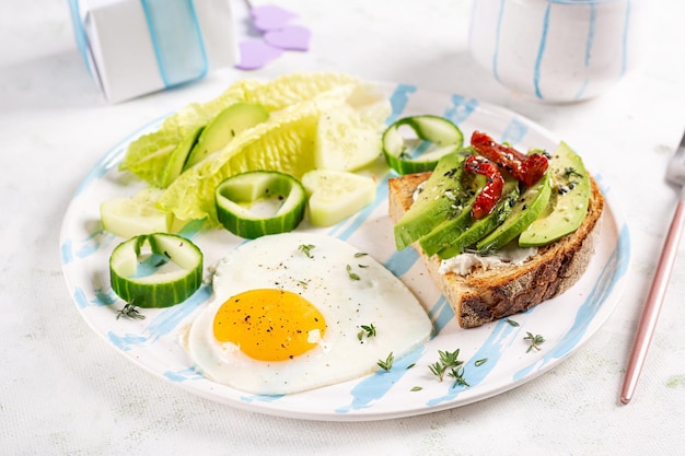 Colazione romantica per San Valentino Uovo fritto e pane tostato con avocado e crema di formaggio