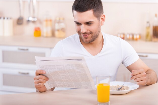 Colazione salutare. Bel giovane che fa una sana colazione mentre è seduto in cucina