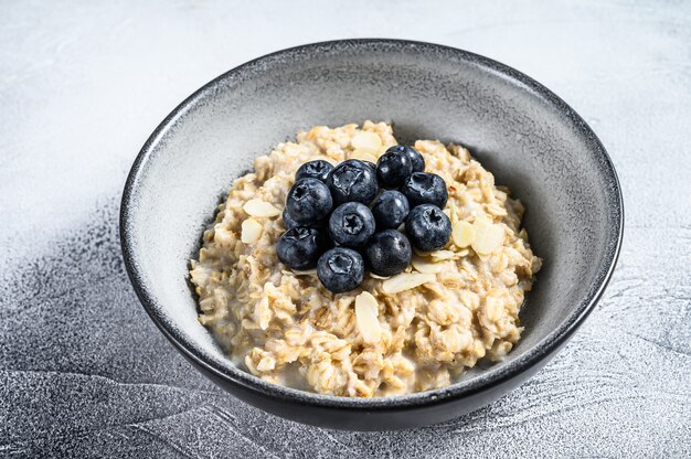 Colazione salutare. Porridge di farina d'avena con mirtilli. Sfondo bianco. Vista dall'alto.